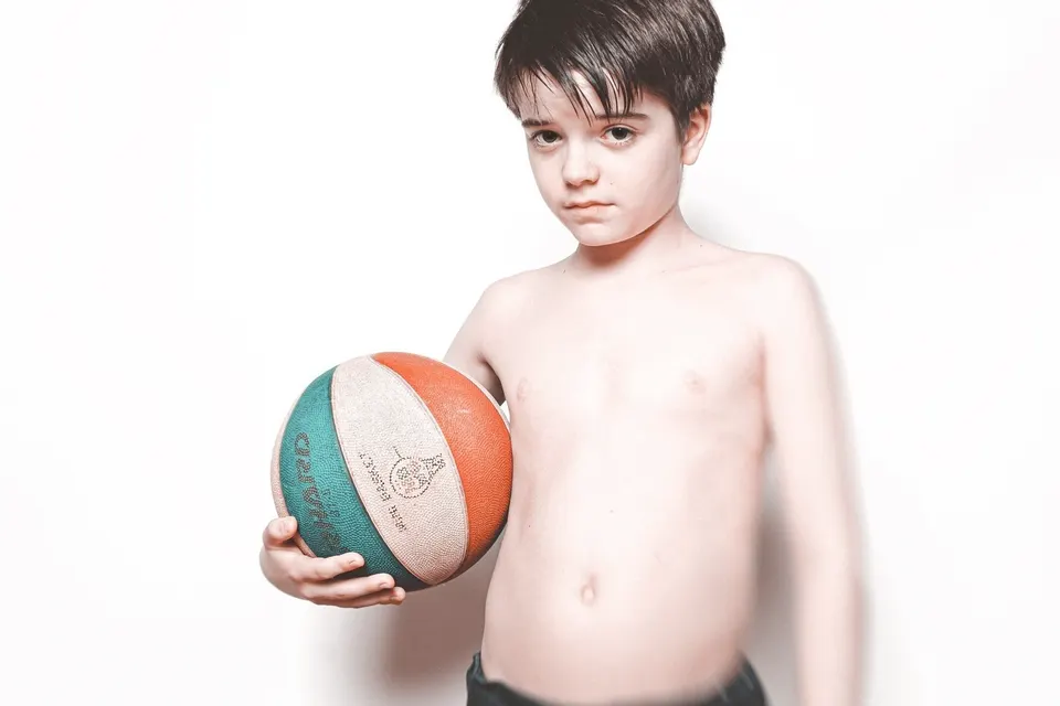 Bub mit Basketball vor weißem Grund