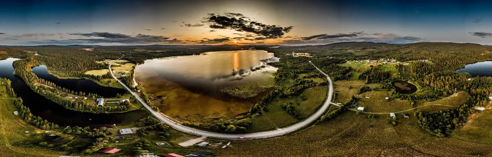 Luftbild-Panorama: Straße im Bogen um einen See bei Sonnenuntergang