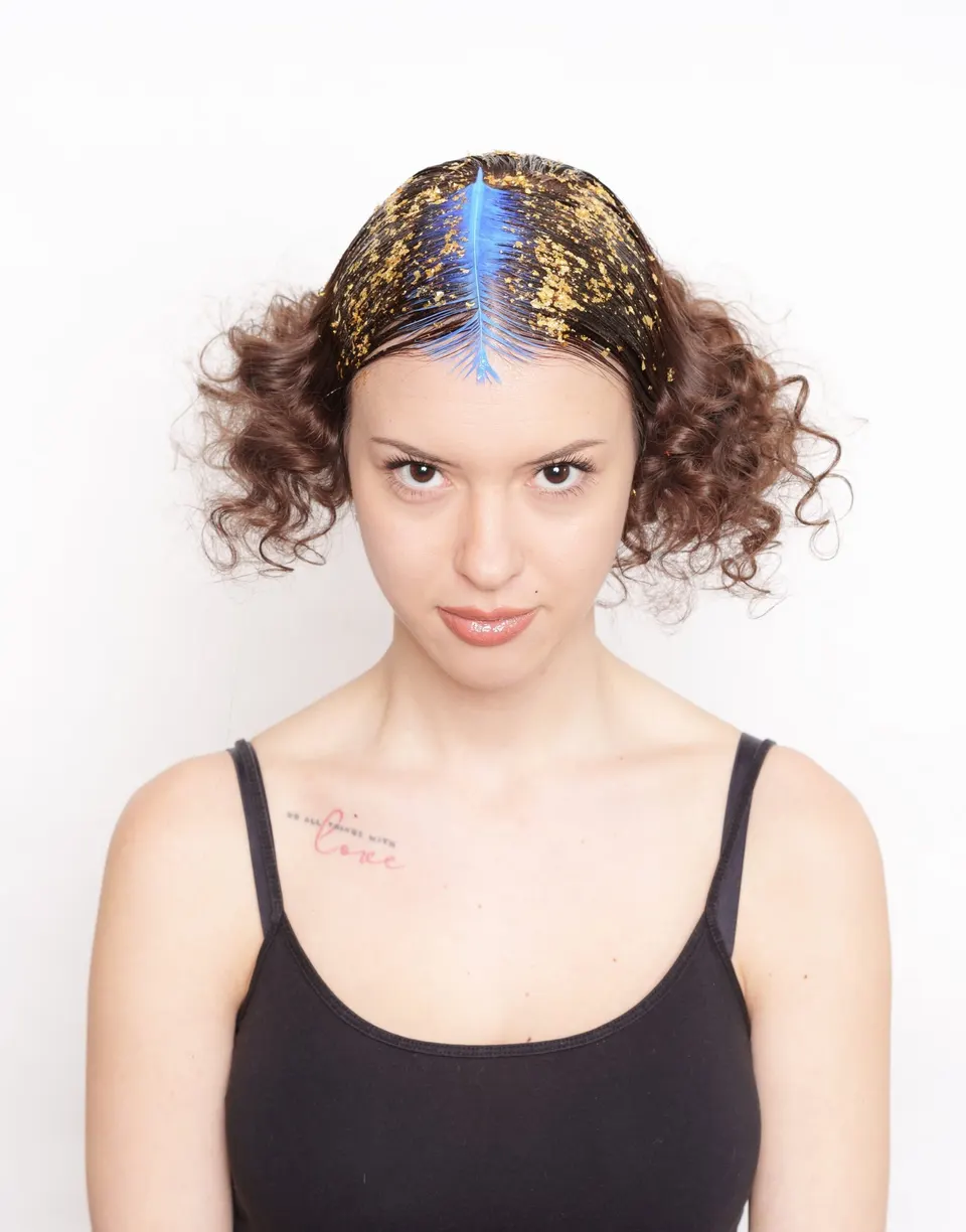 Frau mit Locken und goldenem Haarschmuck vor hellem Grund